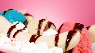Preparing a banana split on a pink background
