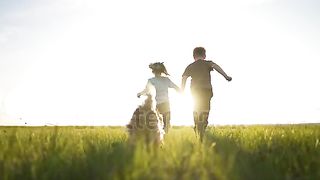 happy girl and boy have fun running with dog
