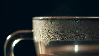 Panning shot of water condensated on a transparent cup containing a  beverage