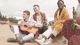Seaside Serenade: Friends Harmonizing with Guitar Melodies by the Ocean
