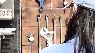 The girl is trying to hang up a monkey wrench