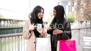 Radiant Moments: Two Multiracial Young Women Share Laughter Watching a Funny Video on a Cellphone
