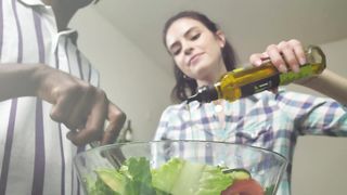 Woman pouring olive oil over salad