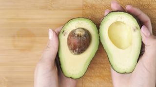 Female hands cutting an avocado in the kitchen