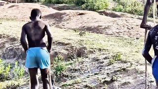 African boys walk with long sticks