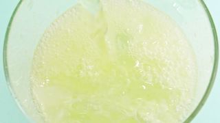 Stream of effervescent soda falling into the glass