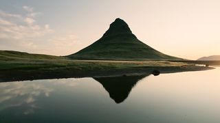 Golden sunrise over Kirkjufell mountain with lake reflection in summer at Iceland