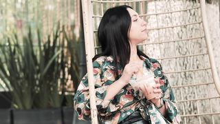Chill Vibes: Girl Relaxes in Hanging Chair with Iced Coffee