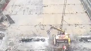 An airborne excavator demolishing a collapsed motorway bridge in Spain
