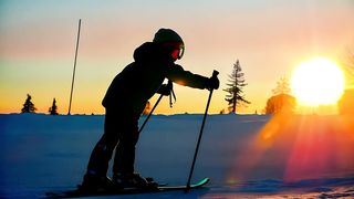 A kid in skiing gear is walking on the snow at dusk - Free Stock Video