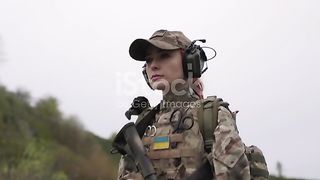 Ukrainian female soldier with her weapon wearing headphones stock video...