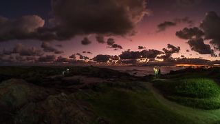Twilight Stroll: Mesmerizing Time-Lapse of Beachgoers with Flashlights at Dusk"