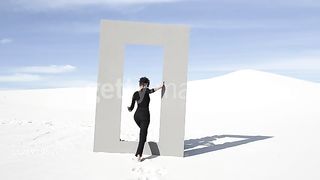 Woman wanders through desert doorframe, wide - stock video African American fashion model walks through doorframe in desert on sunny day