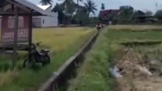 Farmers carry their crops using motorbikes, driving fast over water channels