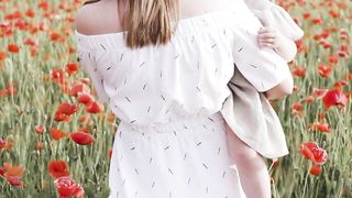 Mother tenderly carries her child, wandering through a picturesque flower field.