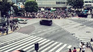 Crowds of people cross a street