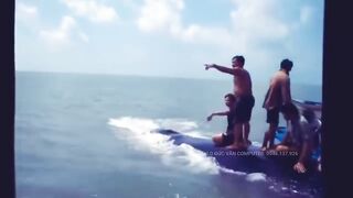 Vietnamese fisherman riding a beached whale after successfully rescuing it.
