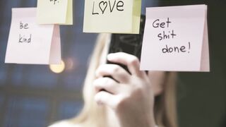 woman taking pictures of motivational words written on stick papers over a mirror