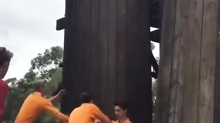 A Band of Bros Uniting in Teamwork to Ascend a Towering 20-Foot Wall