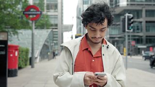 scene depicting a city life concept with a modern young man using his smartphone in the city.