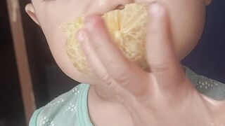 Baby funny way to eat orange