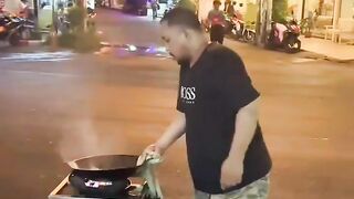 Street vendor tossing the food from the pan to a waiter with a dish across the street