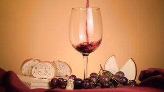 Glass of red wine surrounded by grapes, bread and cheese - adalinetv
