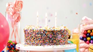 Birthday cake on a table with candies and balloons
