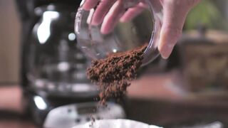 Coffee powder being poured on the coffee maker filter