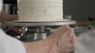 Pastry chef decorating a cake with edible pearls
