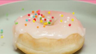 Spreading colorful pieces on a glazed donut