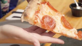 Woman eating a slice of pizza in a close up view