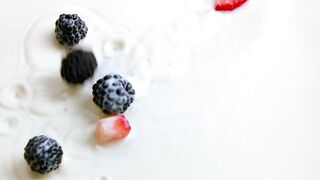 Mix of fresh slices of strawberry and blueberries fall into a milk surface