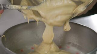 Pastry chef pouring cake mix into baking pans