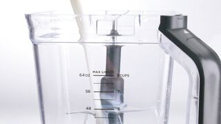 A continuous stream of milk falling into an empty blender
