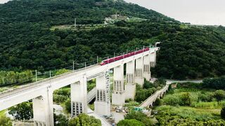 Passenger train passing over a high bridge in the middle of mountains - adalinetv