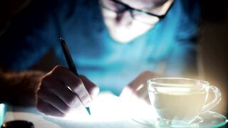 Man with insomnia writes with cup of tea - adalinetv