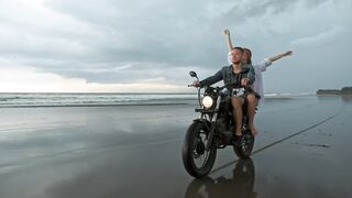 couple-touring-a-beach-riding-a-motorcycle