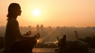 Woman meditating with her dog in the sunset 2
