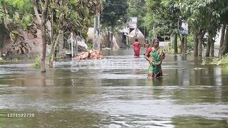 Villagers walk through in the flooded street...