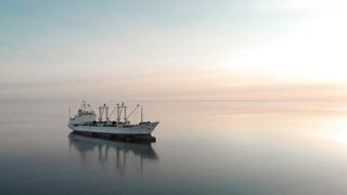 A ship at sea in complete calm during sunset