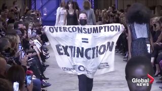 Climate protester sneaks onto Louis Vuitton catwalk at fashion show in Paris.