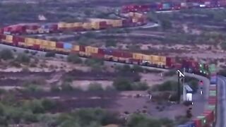 Поезд медленно движется по извилистой железной дороге в пустыне Мохаве