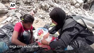 Palestinian woman searches garbage for food as Gaza faces famine.