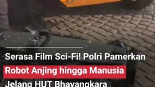 Dua robot berwarna abu-abu, yang menyerupai anjing dan manusia, tampak mengenakan rompi serta topi hitam bertuliskan Polri.