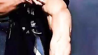 A young man displays his arm muscles and abs after completing a workout.