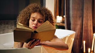 A Woman Reading A Book While Soaked In A Bath Tub