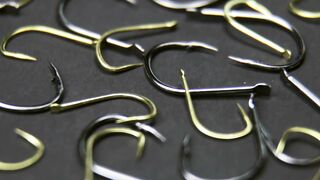 A pile of fishing hooks lined up looks close.