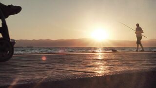 A person is fishing in the sea at sunset.