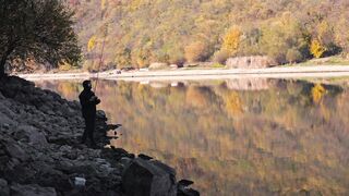 A person fishing on the edge of the lake